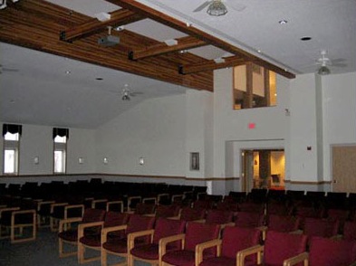 A photo of a large hall with maroon chairs